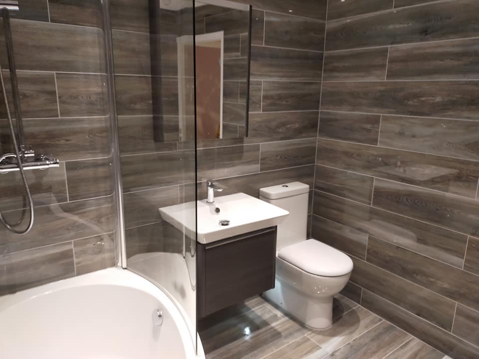 Grey wood-effect tiled bathroom with bath and vanity